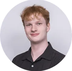 Simple studio-style headshot of Bryan Hogan wearing a black collared shirt on a light gray background
